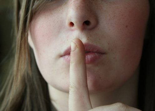 Women with finger to her lips in a 'shh' sign