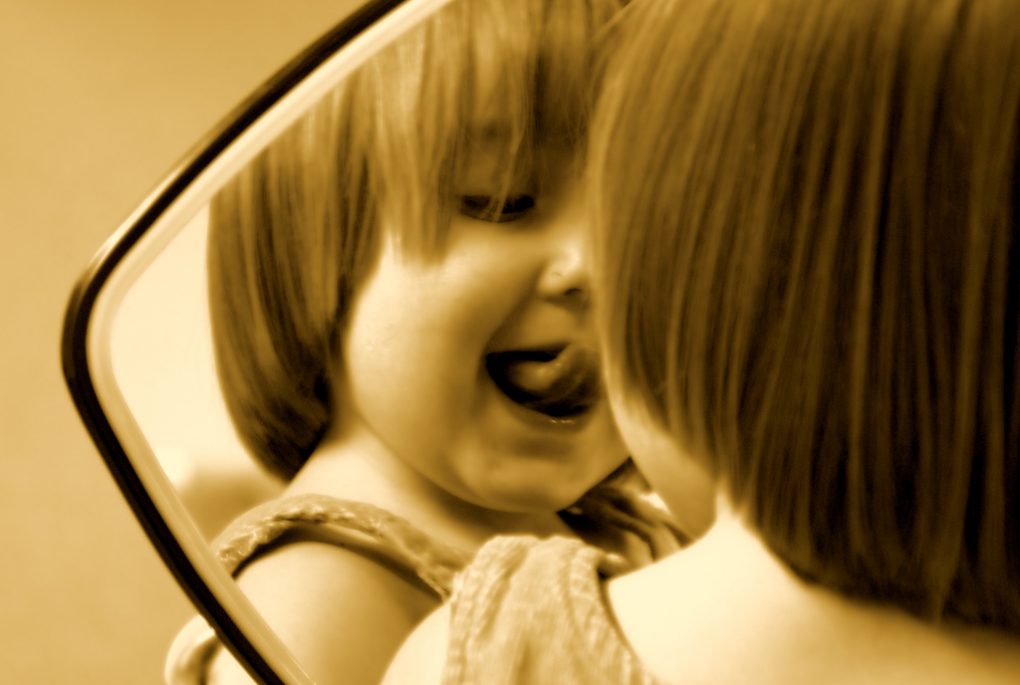 Child pulling a silly face in the mirror