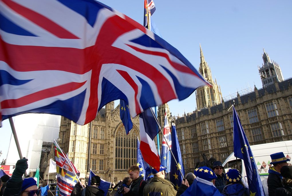Brexit protesters waving Union Jack flags outside Houses of Parliament.