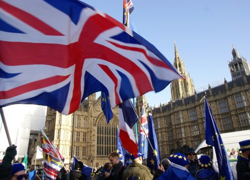 Brexit protesters waving Union Jack flags outside Houses of Parliament.