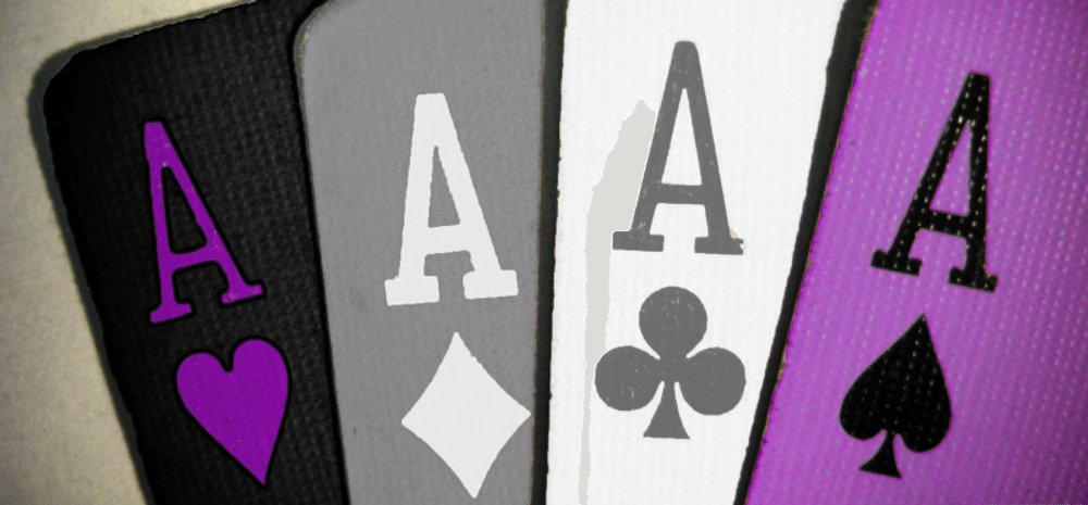 Four Ace playing cards in the colours of the asexual flag - purple, grey, black and white